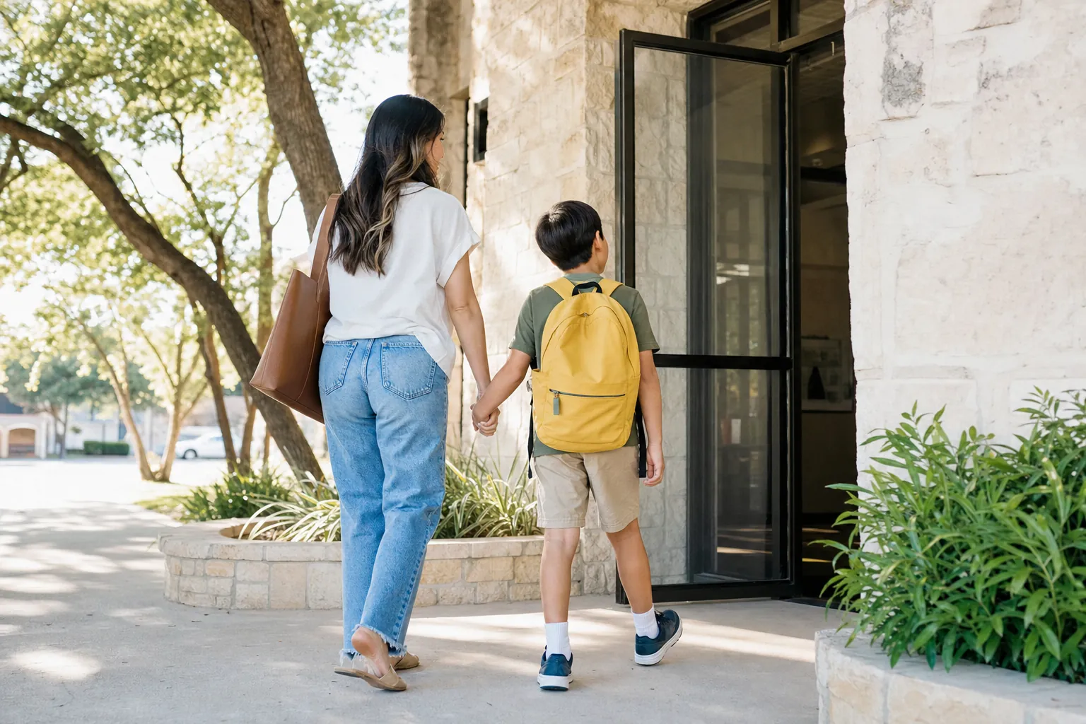 A mother and son walking into an office building on a sunny morning
