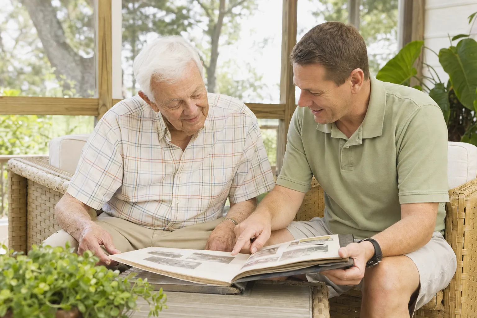 An older man and his son looking through a photo album on a porch