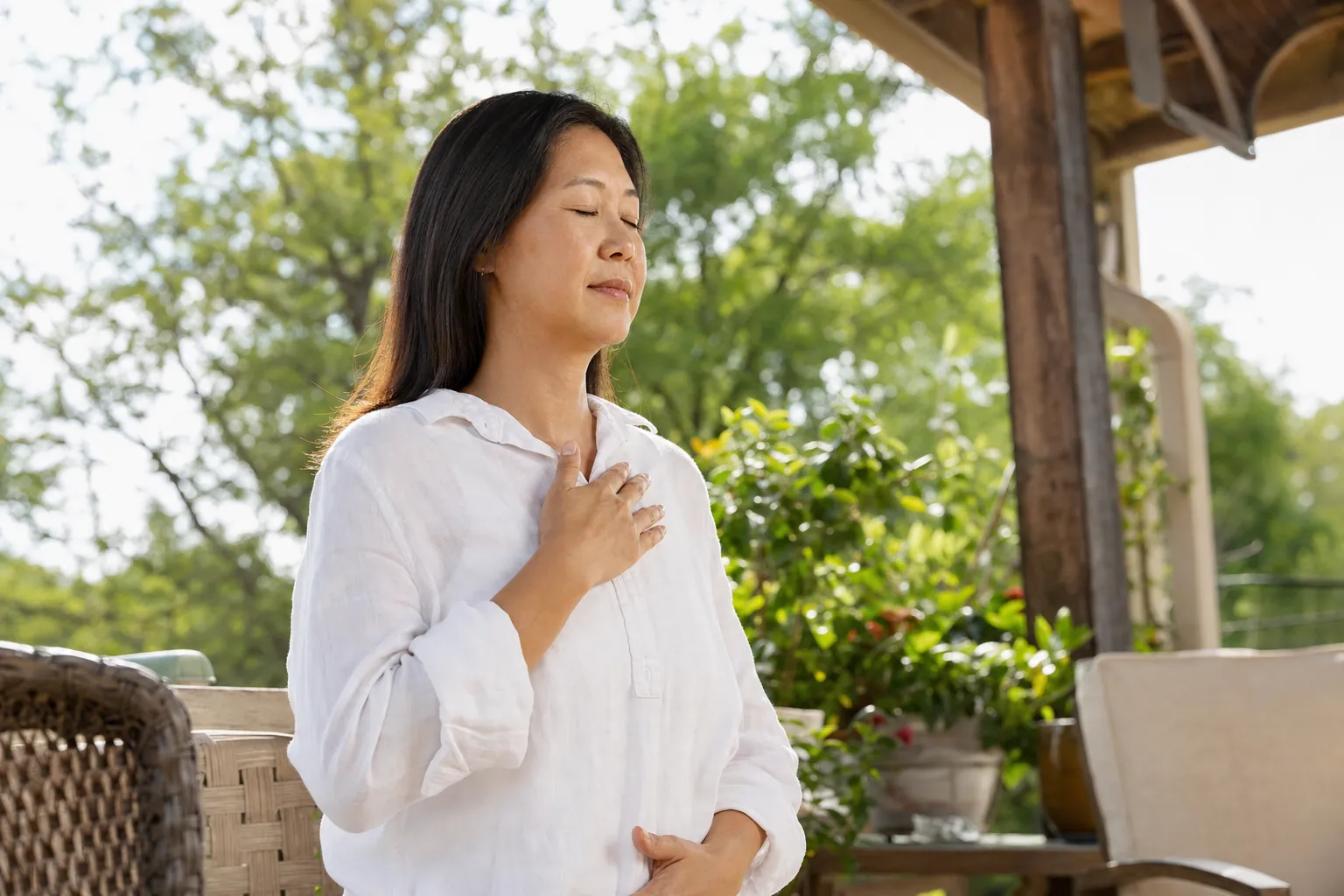 A woman doing a breathing exercise on a sunny patio