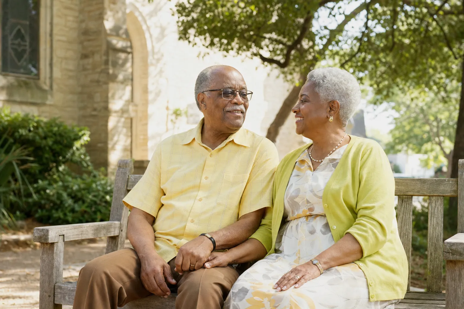 An older couple holding hands on a garden bench