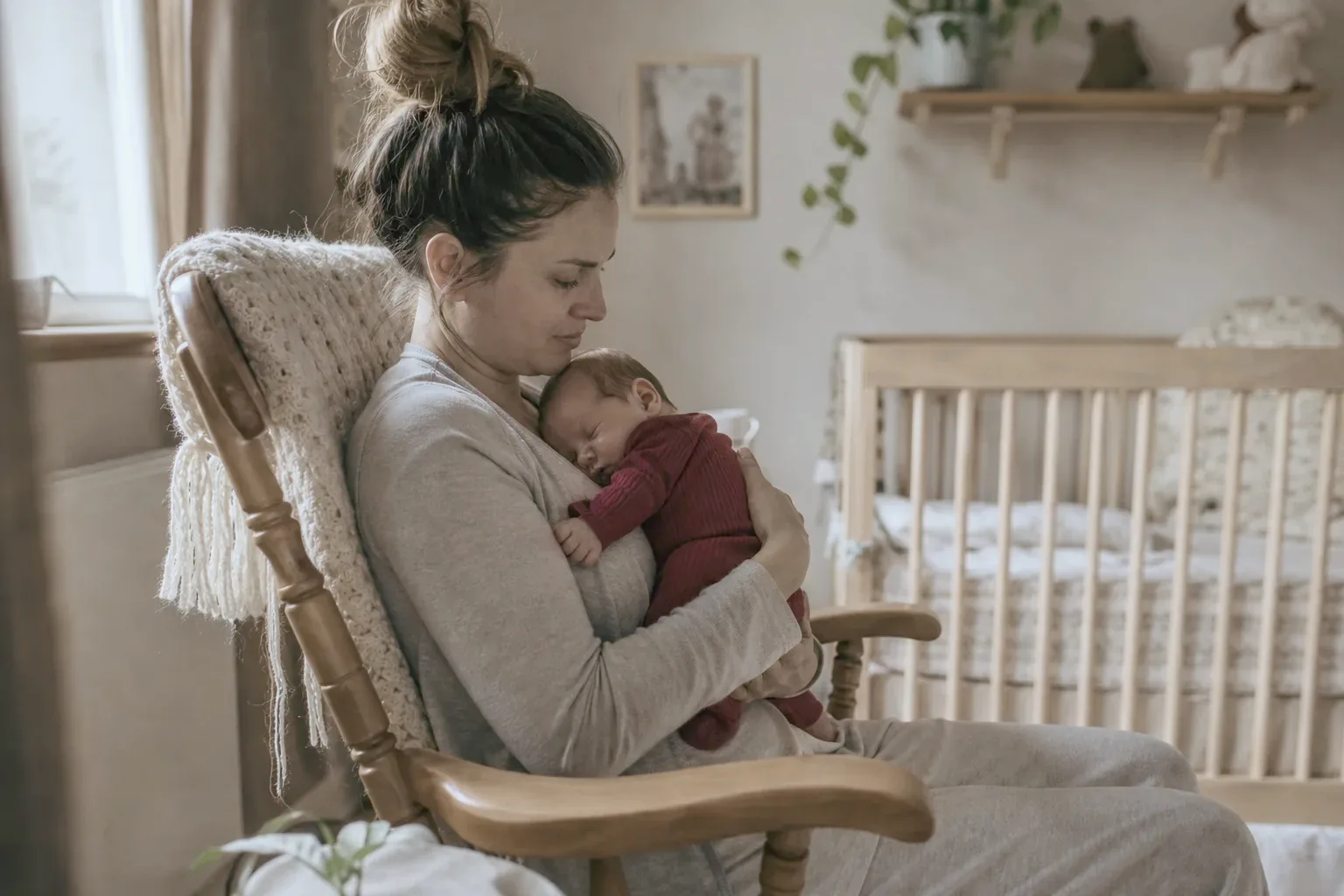 A new mother in a rocking chair holding her sleeping newborn